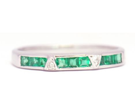 Precious metal emerald and diamond half eternity ring, alternate set with a group of 3 calibre cut emeralds and 2 small diamo