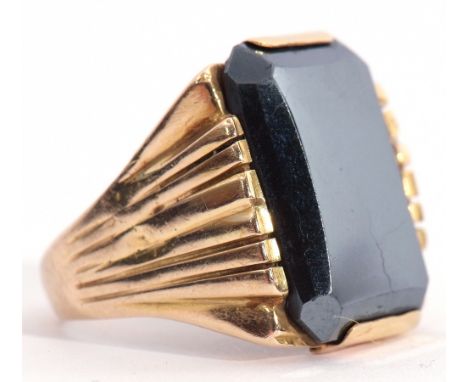 Mid-grade yellow metal and haematite signet ring, the rectangular shaped panel 18 x 9mm, raised between engraved angular shou