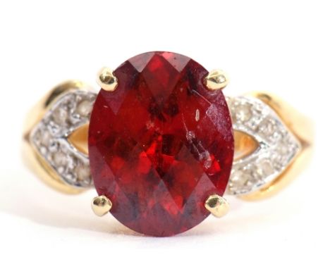 Modern garnet and diamond dress ring, the oval faceted garnet raised between diamond pierced shoulders, stamped 750, size K/L