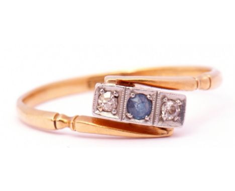 18ct stamped sapphire and diamond ring of cross over design, the central round faceted sapphire between 2 diamonds, all in bo