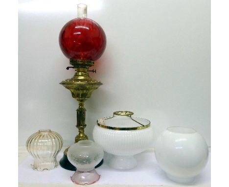 A brass oil lamp and four glass shades