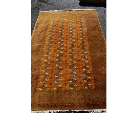 An old Turkoman carpet, having repeated central field, on yellow ground with geometric borders, 310 x 200cm. 