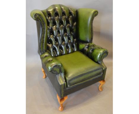 A Green Leather Button Upholstered and Studded Wingback Armchair with cabriole legs