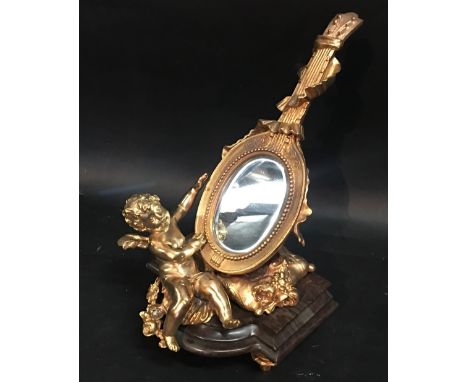 A French Ormolu Table Mirror in the form of a Musical Instrument with Putti Cresting upon a Cushion, the whole upon a variega