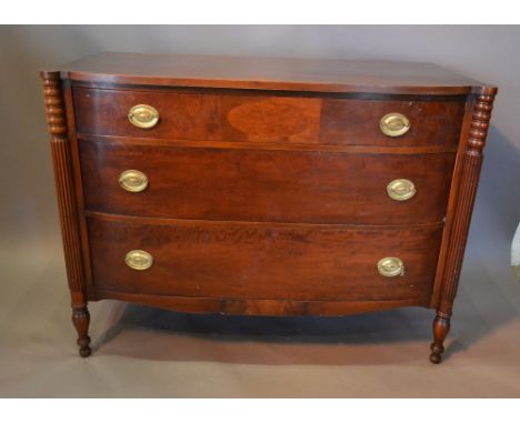 An Early 20th Century Mahogany Bow Fronted Commode with three drawers and oval brass handles flanked by turned and reeded col