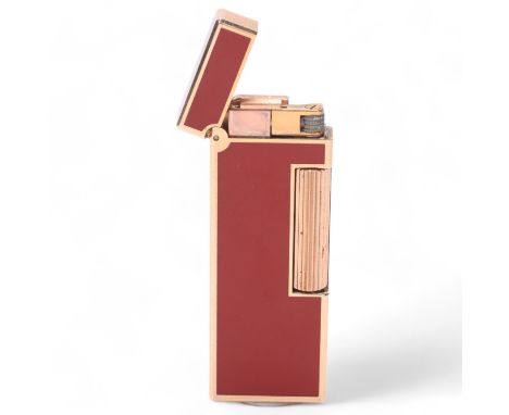 A Dunhill slimline Rollagas lighter, gold plated with red lacquer body, makers marks to base, No118778, length 6.3cmsome surf