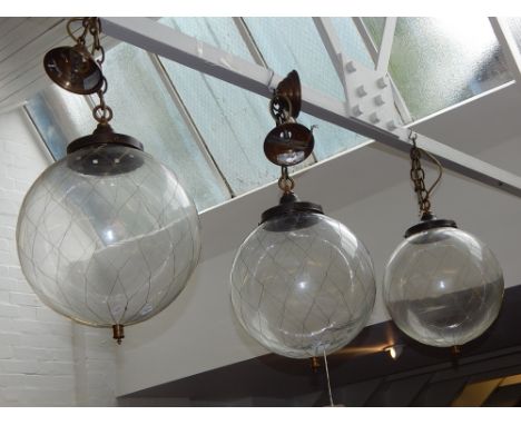 Three clear glass globe hanging lamp, decorated with a fine web of brass wire, suspended form a chain, D. 38cm.