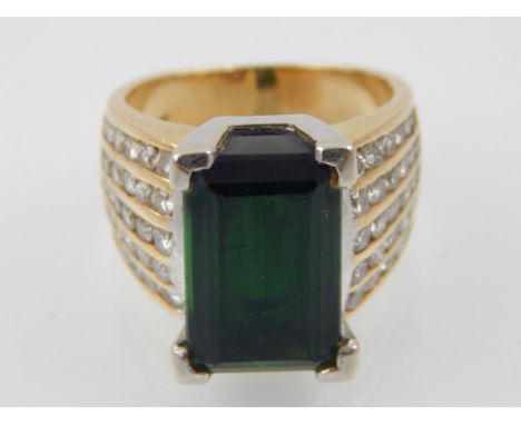 A green tourmaline dress ring, set in a yellow metal band with diamond set shoulders, 10 g.
