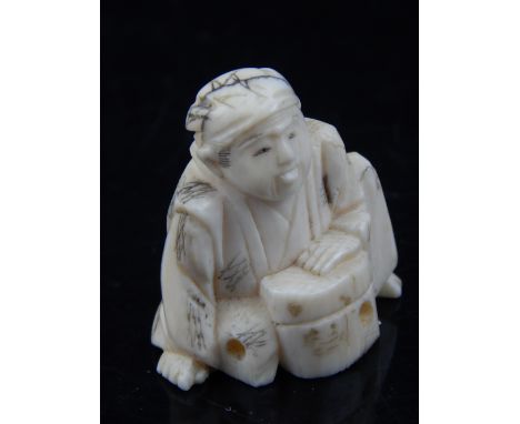 A late 19th / early 20th century ivory netsuke of a seated gentleman, H. 3cm