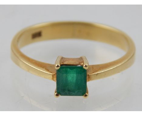 An 18 carat yellow gold and emerald solitaire ring, stamped 18k to shank