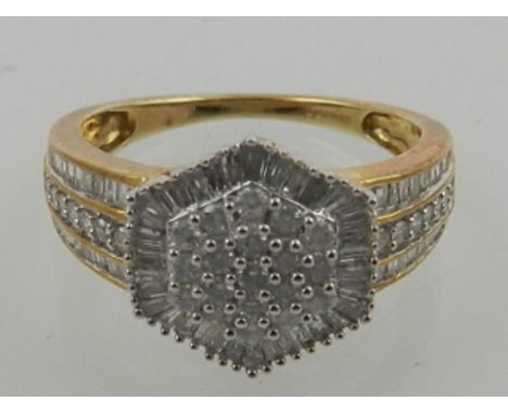 A 9 carat yellow gold and diamond cluster ring, set round cut and baguette diamonds within an hexagonal mount, the shoulders 