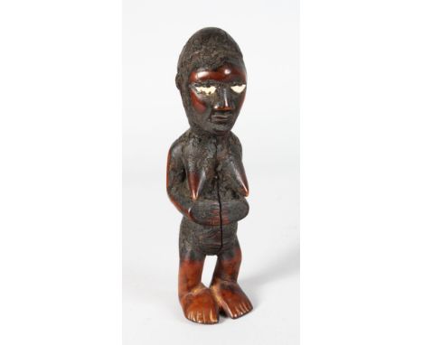A CARVED WOOD TRIBAL FEMALE FIGURE, with crusty bone eyes. 9ins high.
