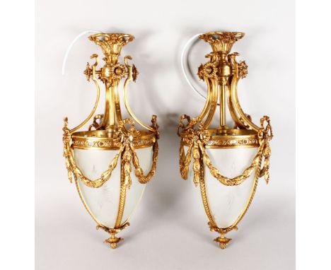 A PAIR OF GILT METAL AND FROSTED GLASS HANGING LANTERNS with garlands and pineapple finial. 24ins long.