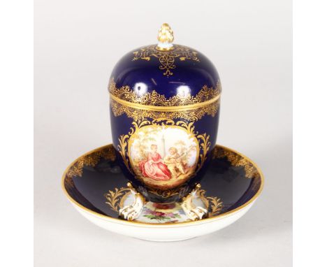 A 19TH CENTURY MEISSEN BLUE GROUND CUP, COVER AND STAND, the cup edged in gilt and painted with an oval, a young lady and boy