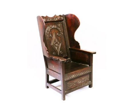 A RARE EARLY 18TH CENTURY OAK LAMBING CHAIR, with wings, panel seat and carved decoration, dated 1730.