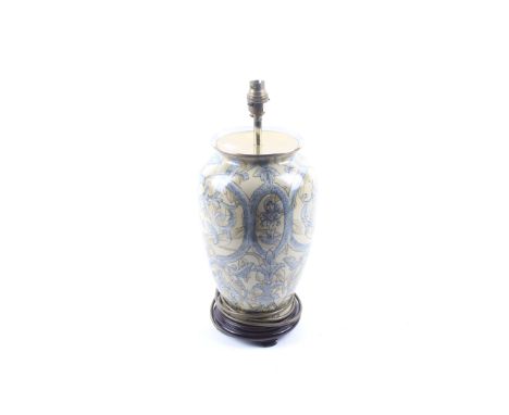 A 20th century ceramic table lamp. Of balaster form, mounted on a wooden stand. Decorated with a stylized leaf pattern in two