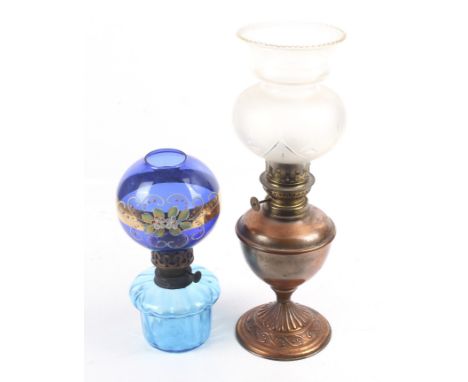 Two vintage oil lamps. One with a copper base and clear glass reservoir, the other with a blue glass reservoir and blue glass