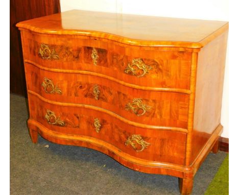 An early 19thC German walnut serpentine commode chest, of three drawers, each with an elaborate escutcheon and handles, the t
