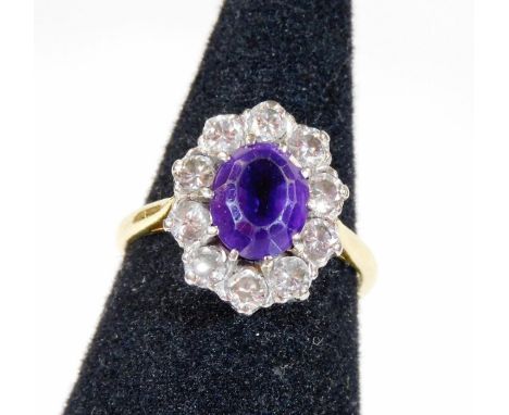 An amethyst and diamond cluster ring, with central oval cut amethyst surrounded by ten round brilliant cut diamonds, each in 