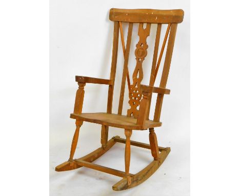 An early 20thC lightwood rocking chair, with comb top, pierced vertical splat, shaped arms and seat on turned legs, joined by