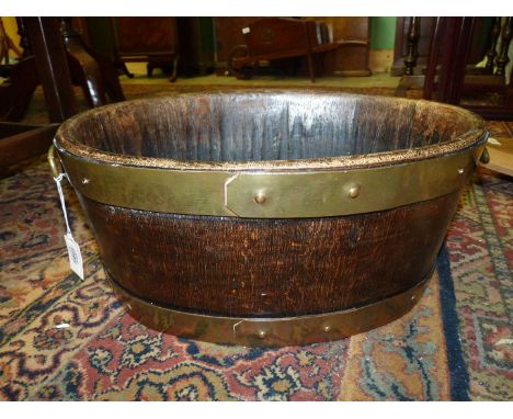 An early 20th century coopered oak and brass bound oval trough with original brass ring handles, 17" x 13".