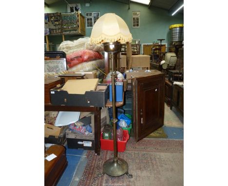 An adjustable brass standard lamp on a circular base with three flattened feet.