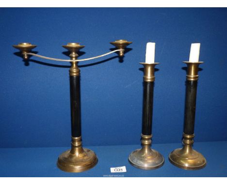 A set of brass and black columned Candlesticks and a three branch Candelabra.
