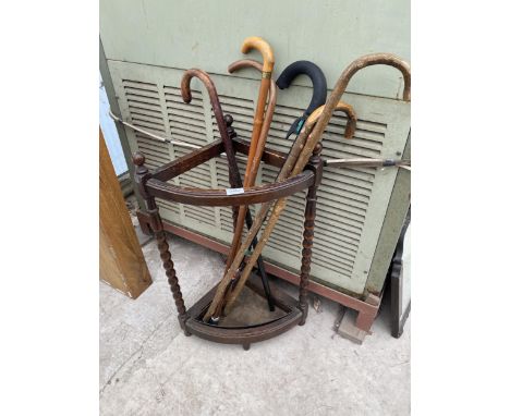 AN EARLY 20TH CENTURY OAK CORNER STICK STAND ON BOBBIN LEGS WITH SIX VARIOUS WALKING STICKS 