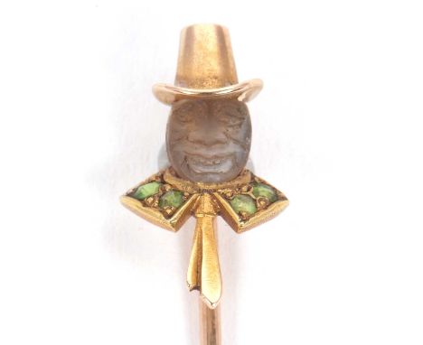 A leprechaun stick pin, the carved moonstone face set with a peridot collar and yellow metal tie and hat, all in unmarked yel
