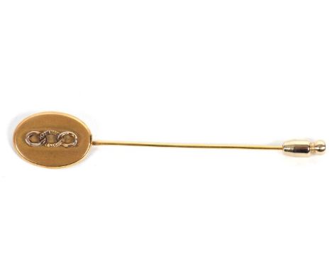 A gold tie pin, the oval disc with chain link decoration, stamped to reverse 10K, on unmarked pin, 1.5g, plus gilt metal stop