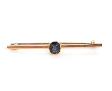 A spinel bar brooch, the cushion cut dark blue spinel (possibly synthetic), collet mounted to a plain bar marked '15ct', 45mm