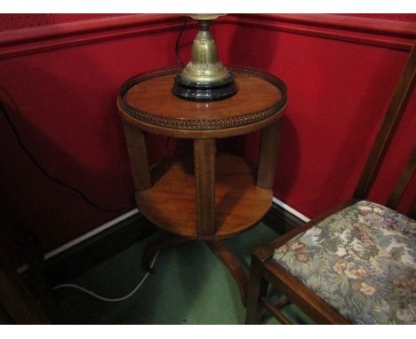 An Edwardian strung inlaid mahogany revolving circular bookshelf with brass balustrade gallery above a tripod base on brass c
