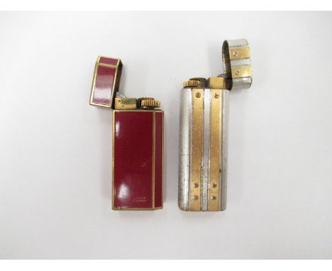 Two Cartier lighters in red enamel/gold plate, No. A83680 and base metal/gold plated (worn and pitted), No. 6339 T (2)   