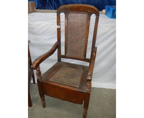 An oak chair commode the cane back.