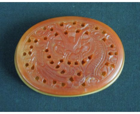 A CHINESE CARVED HORN, OVAL SHAPED, BELT OR SASH BUCKLE, carved and pierced with dragon designs with two lugs to the back. 6 