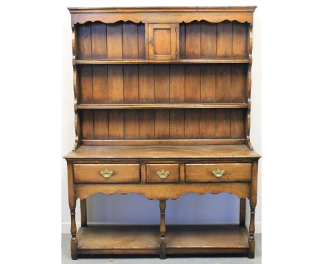 18TH CENTURY STYLE WELSH OAK DRESSER, having moulded cornice over boarded, two shelf back with small centre cupboard, the bas