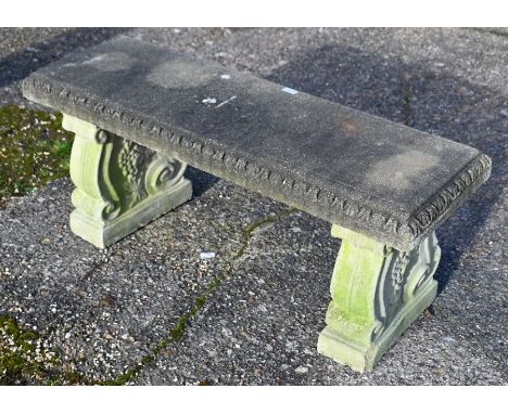 A weathered three piece cast stone garden bench