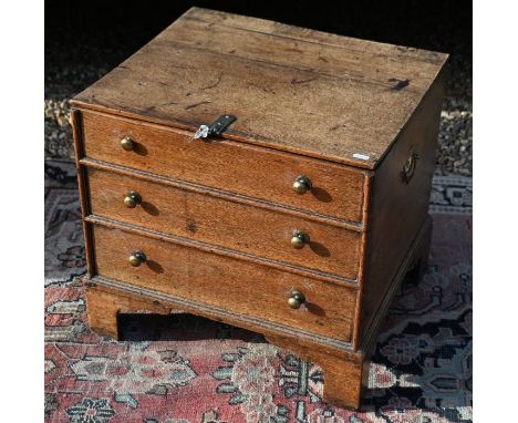 A Georgian oak box commode with hinged panelled top and three dummy drawers with brass handles, raised on bracket feet, 50 cm