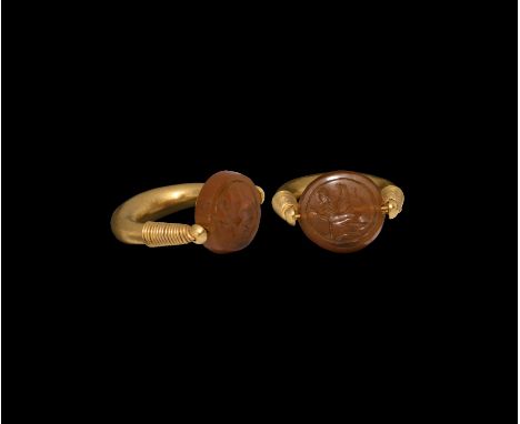 5th-3rd century BC. A gold penannular ring with coiled filigree to the shoulders, swivel carnelian cabochon bezel with intagl