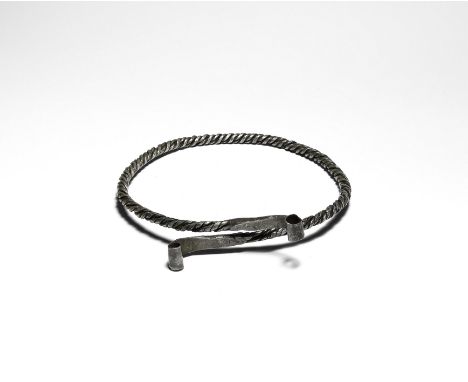 10th-12th century AD. A silver neck-ring with round-section shank of coiled facetted rods, each end forged to a square-sectio
