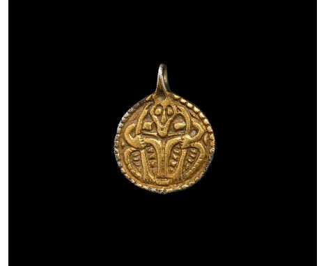 9th-10th century AD. A discoid silver-gilt pendant with integral loop, border enclosing a low-relief image of a male facing m