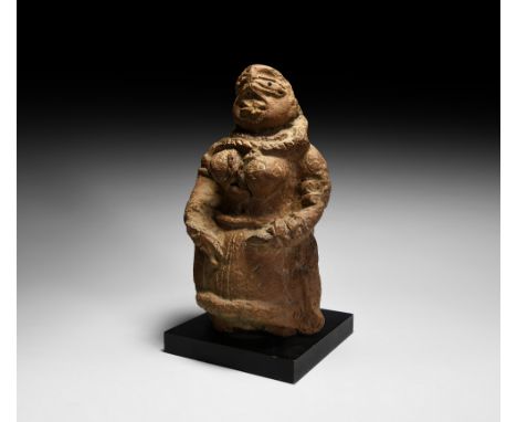 3rd millennium BC. A conical ceramic statue of a female shown with a voluminous skirt, ropework detailing to the collar, wais