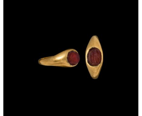 2nd-4th century AD. A gold ring with D-section hoop expanding to an ellipsoidal bezel; cut and polished carnelian gemstone wi