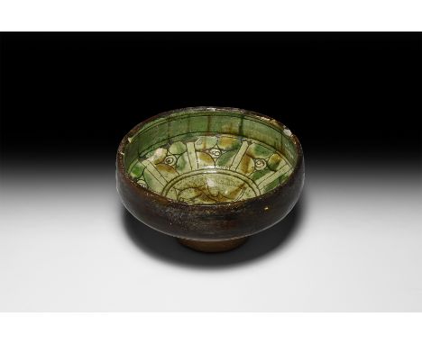 12th-15th century AD. A ceramic sgraffito bowl with carinated body and deep foot; ochre and green slip on a cream ground on t