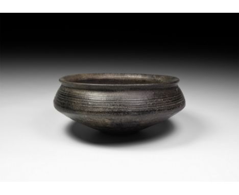 Mid 3rd-2nd millennium BC. A carinated bowl with everted rim and shallow circular foot; the upper body with comb tooth decora