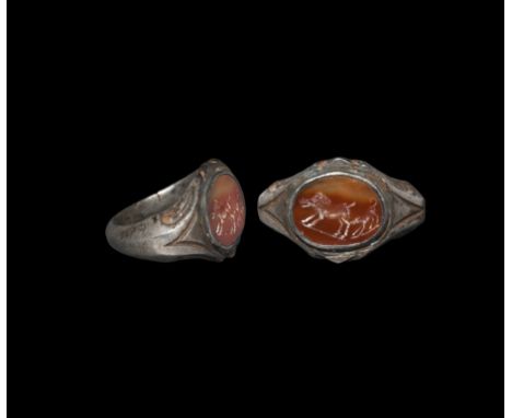 3rd century AD. A silver ring with carinated hoop, expanding at the shoulders to a bezel decorated with scrollwork; set with 