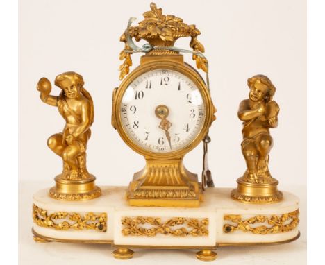 A gilt metal mounted mantel clock, the white enamel dial with Arabic numerals, flanked by musical putti on a white marble bas