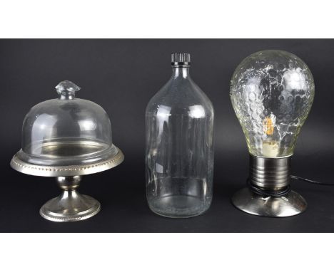 A Glass Bottle with Ribbed Body, Small Silver Plated Cake Stand with Glass Cover and a Novelty Table Lamp in the Form of a Li