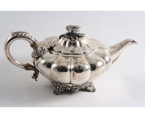 A WILLIAM IV TEA POT of melon-fluted form with a leaf-capped, C-scroll handle, shell & foliate feet and a flower finial, init