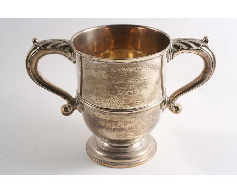 AN EARLY 20TH CENTURY TWO-HANDLED TROPHY CUP with leaf-cupped scroll handles and an inscription on one side relating to the "